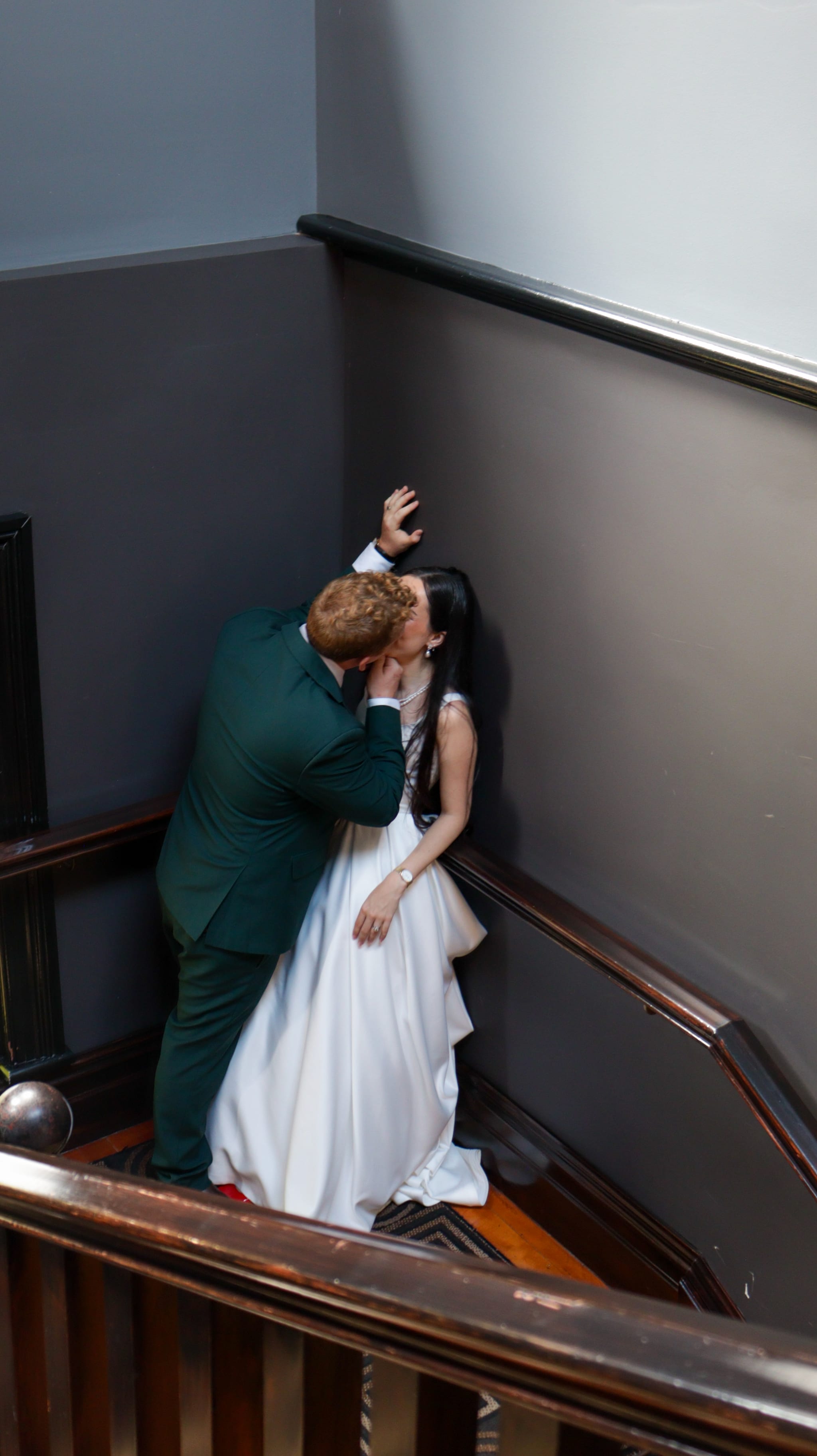 bride being kissed on staircase up against the wall